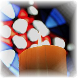 Eine Kerze mit Kirchenfenster im Hintergrund